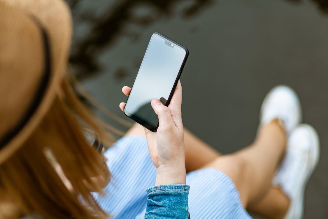 Gratis Persona Sosteniendo Smartphone Blanco Sentado Foto de stock