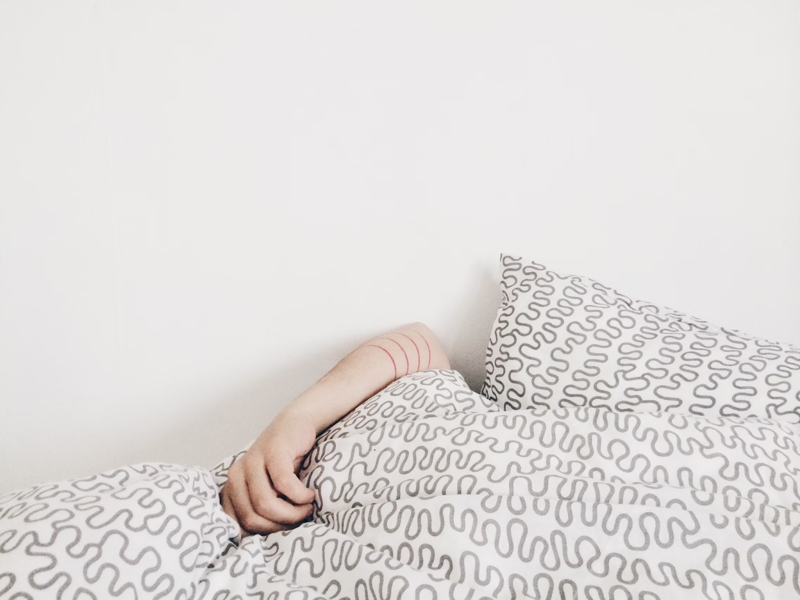 Person laying on bed with white sheets