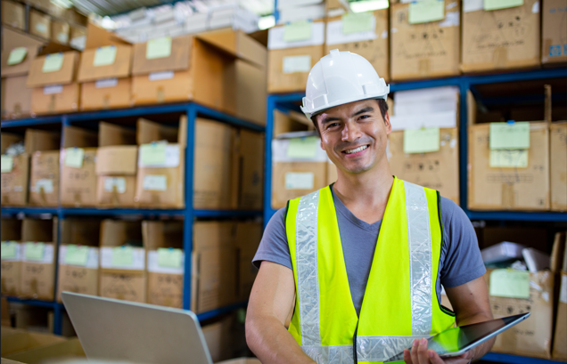 Trabajador logístico en un almacén, revisando la información del TMS de pinit en sus dispositivos. 