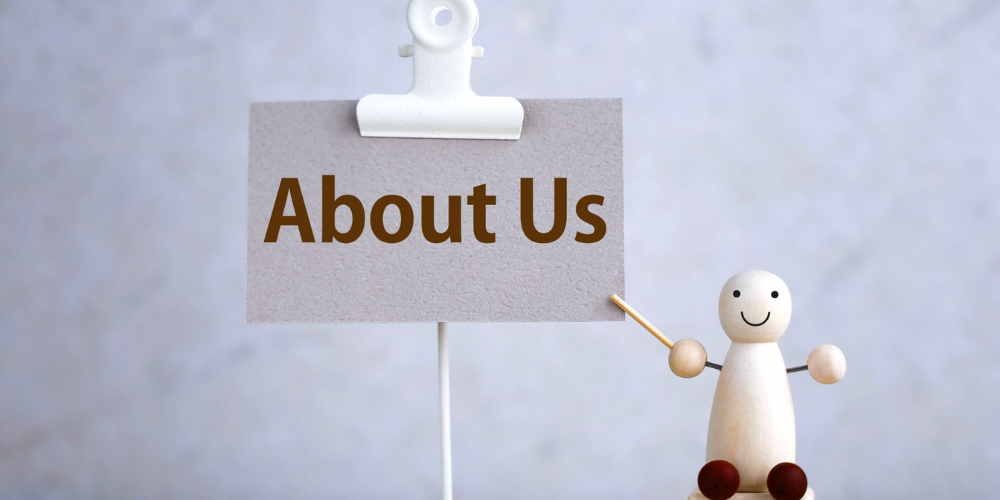 「About Us」と書かれたカードを、木製の人形が指し棒で示している
