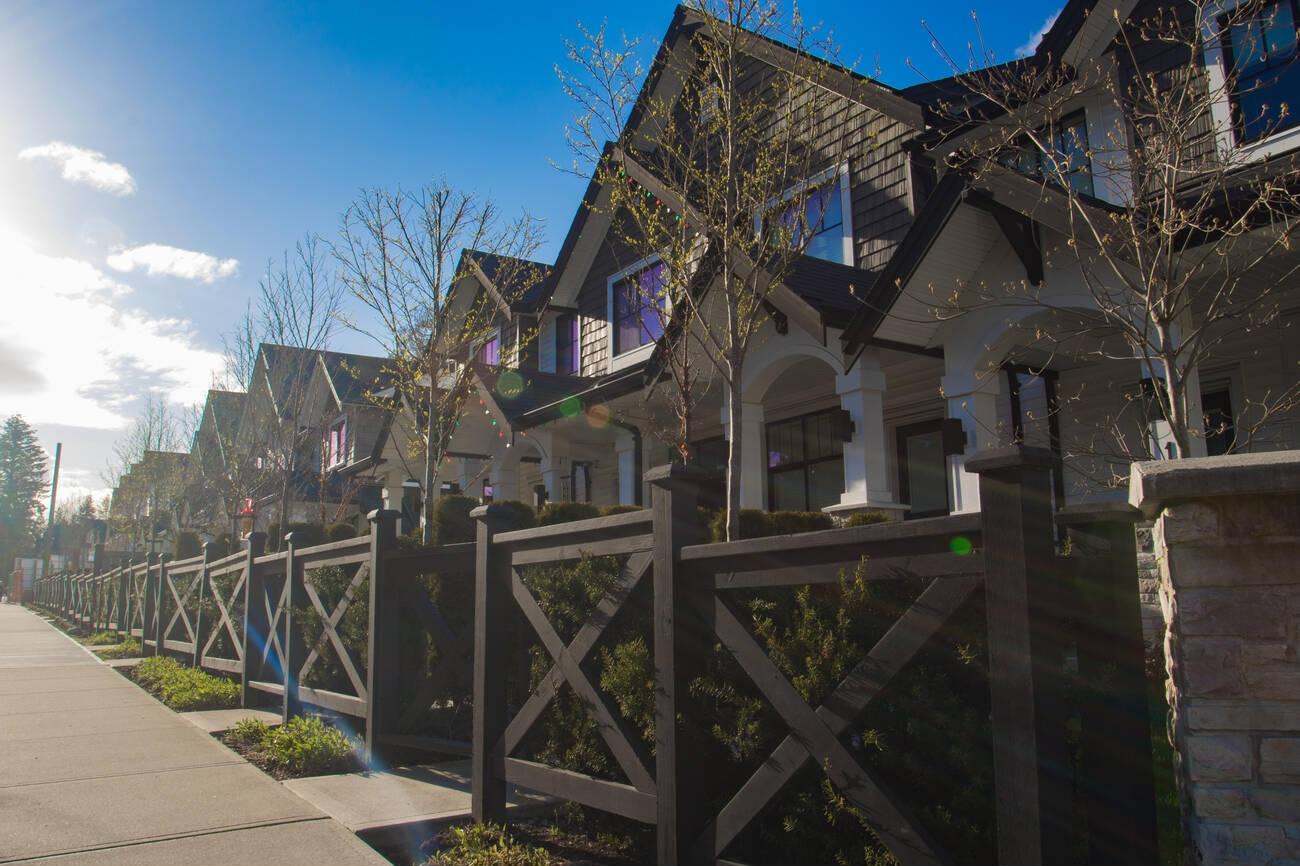 A row of houses with a fence

Description automatically generated