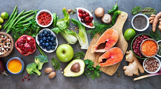 A colourful assortment of fruits, vegetables, fish, and other healthy foods arranged on a table.