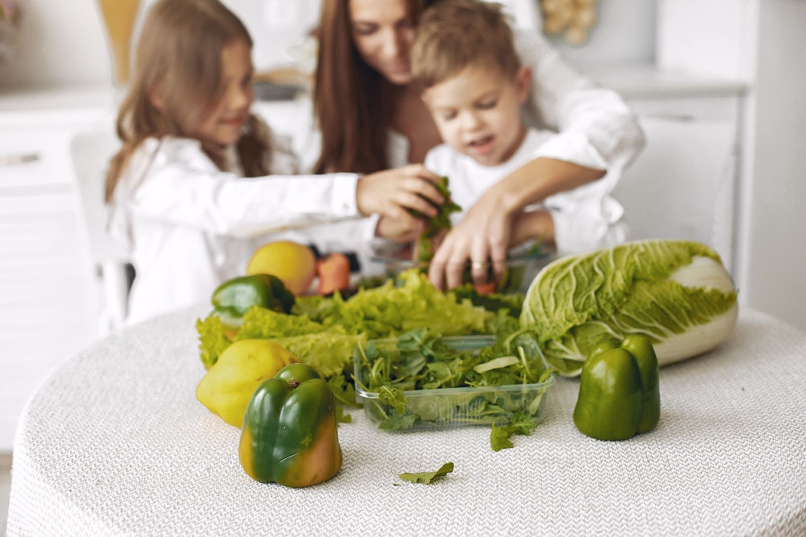 Mother and children making a salad with green vegetables