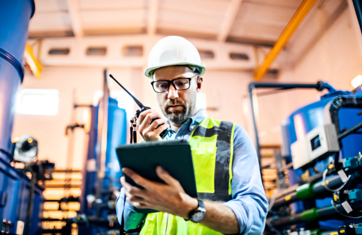 A person in a hard hat and safety vest holding a tablet

Description automatically generated