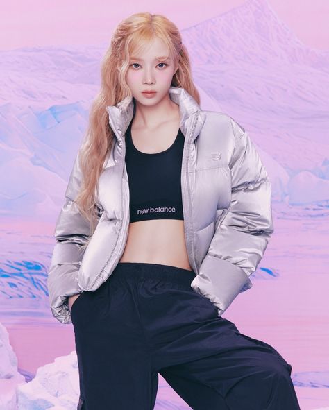 This containa picture of Aespa Winter with long hair wearing a silver jacket and black pants standing in front of snow covered mountains