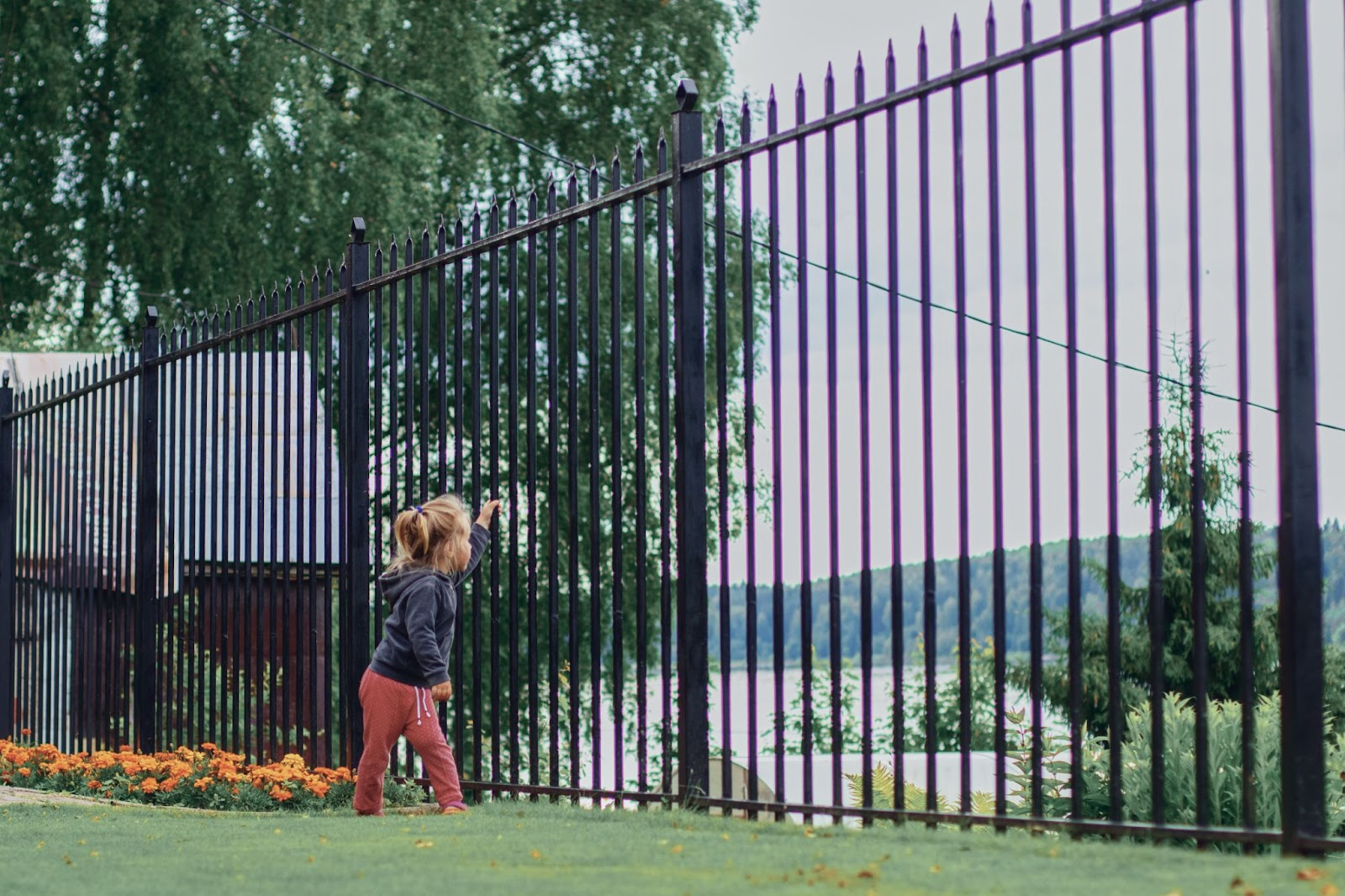 Young girl next to aluminum fence post. 