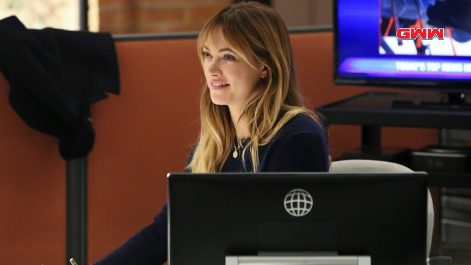 Ellie NCIS agent working diligently at her desk, smiling.