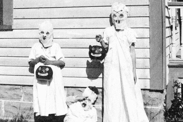 Three children dressed up as ghosts, ready for trick or treating.