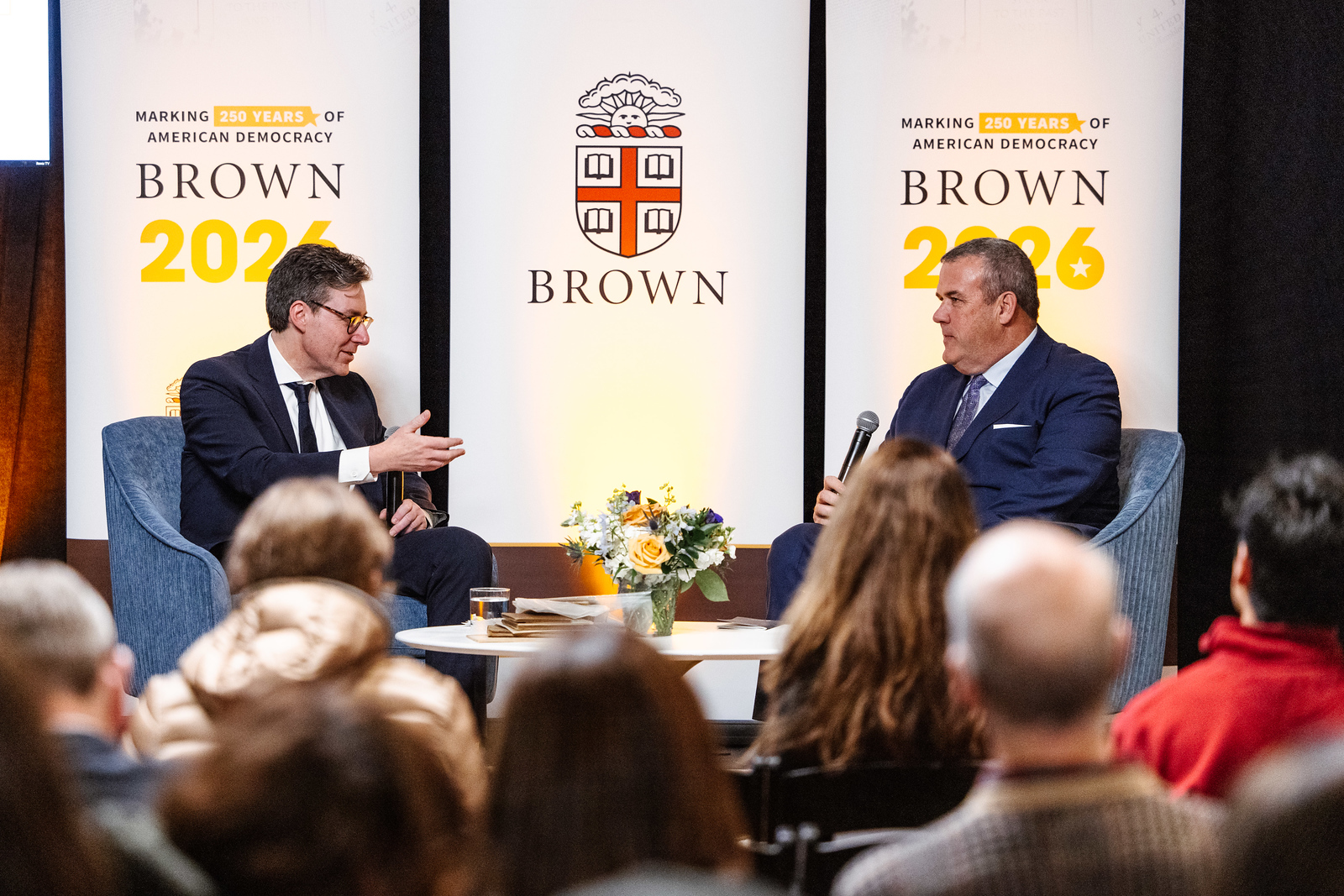 Gregg Amore and Eric Slauter are pictured on a stage. The image also shows some of the audience and banners for Brown and Brown 2026.