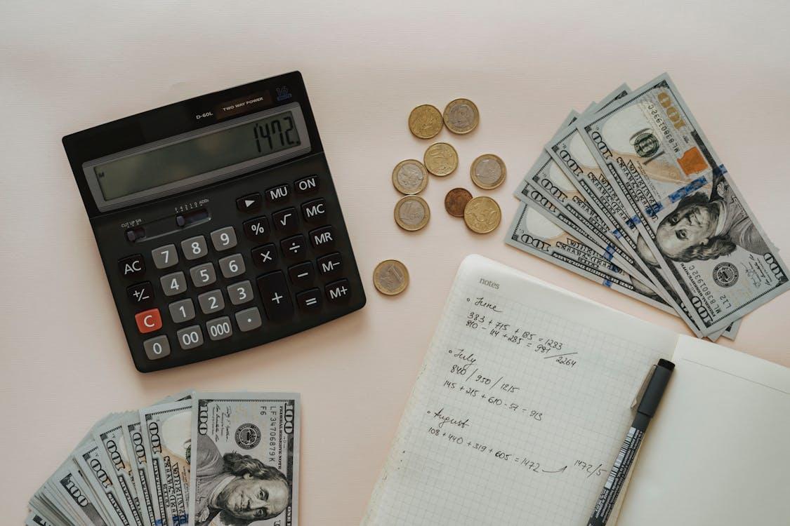 free flat lay of calculator, cash, coins, and handwritten notes for budget planning. stock photo