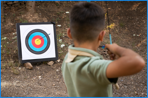 Little boy shooting a bow aiming at the target