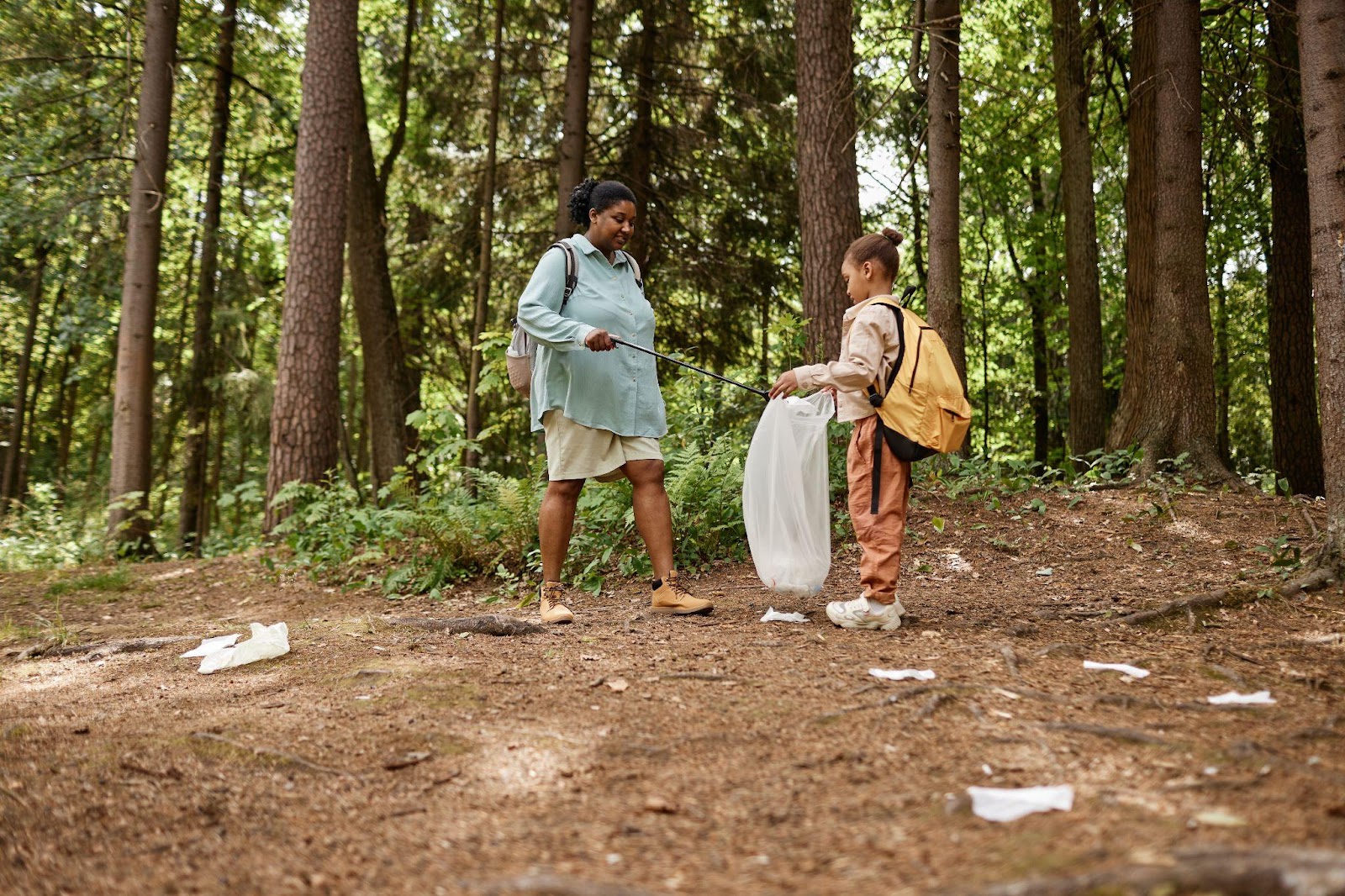 woman and child collecting trash in a woodland