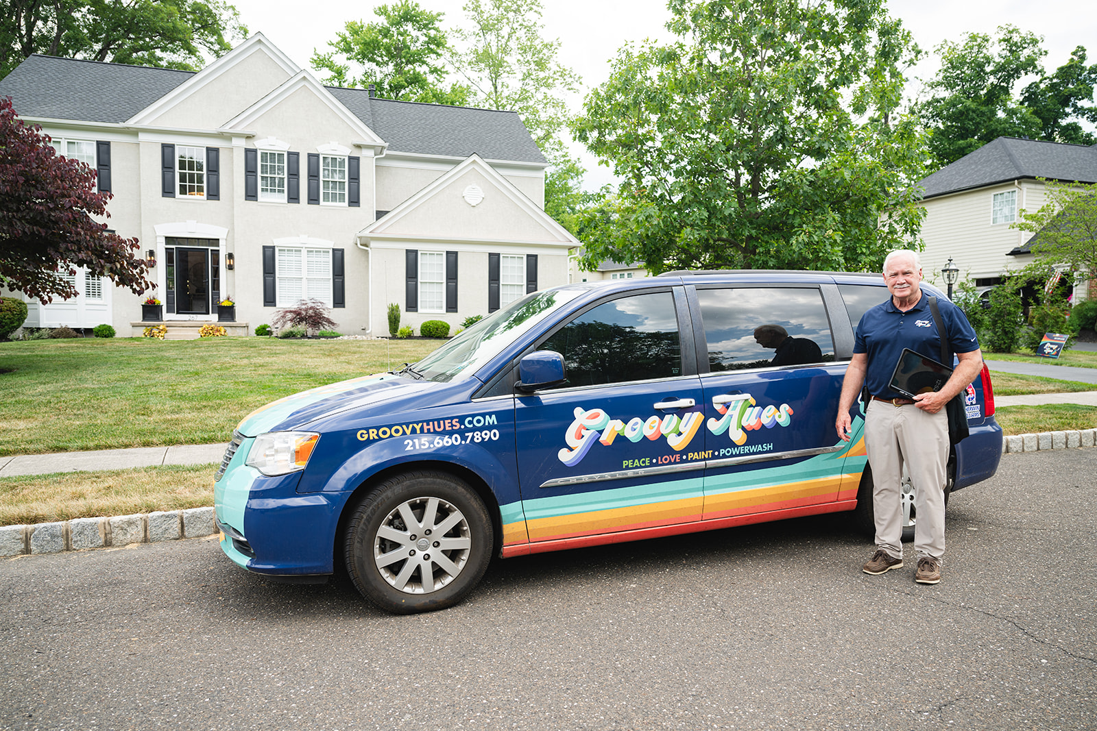 Groovy Hues Painting of Philadelphia consultant stands next to the company's branded van in a Main Line, PA, neighborhood.