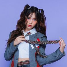 This contains a picture of NewJeans Hyein's  wearing a school uniform and has a tie around her neck while standing against a purple background