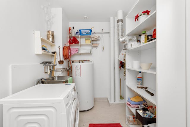 Laundry room with water heater in corner of the room