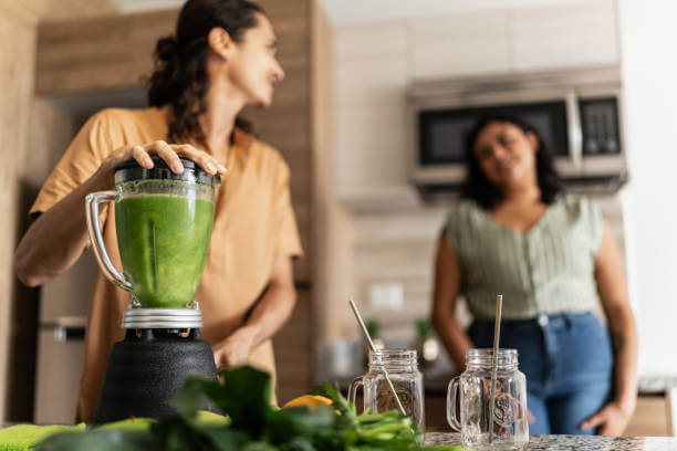 A woman preparing green juice in a blender as part of her 7-day detox plan.