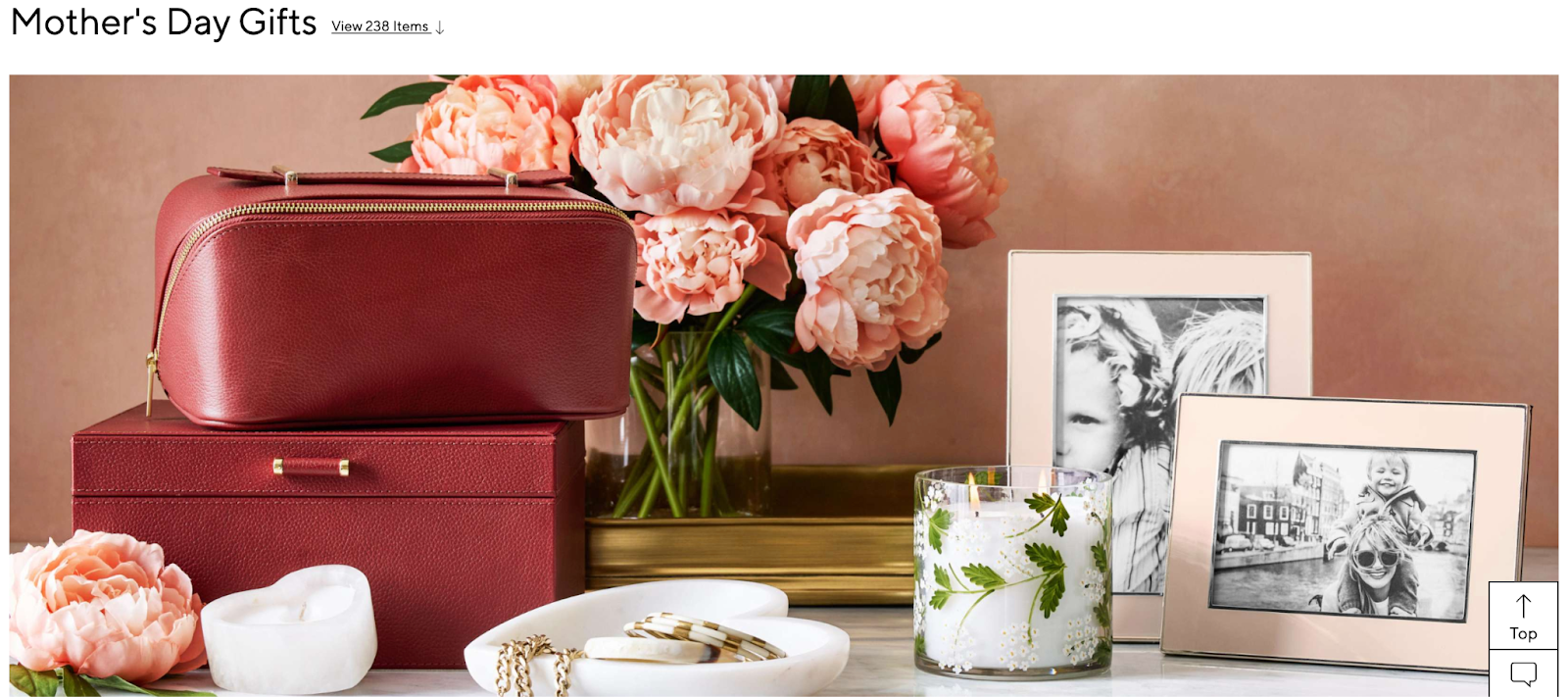 Luxury gift setup on a marble surface featuring a red leather toiletry bag and matching box, framed black-and-white family photos, a floral-embedded glass candle, jewelry dish with gold chains, and pink peonies in the background, creating a soft, elegant, and feminine aesthetic.