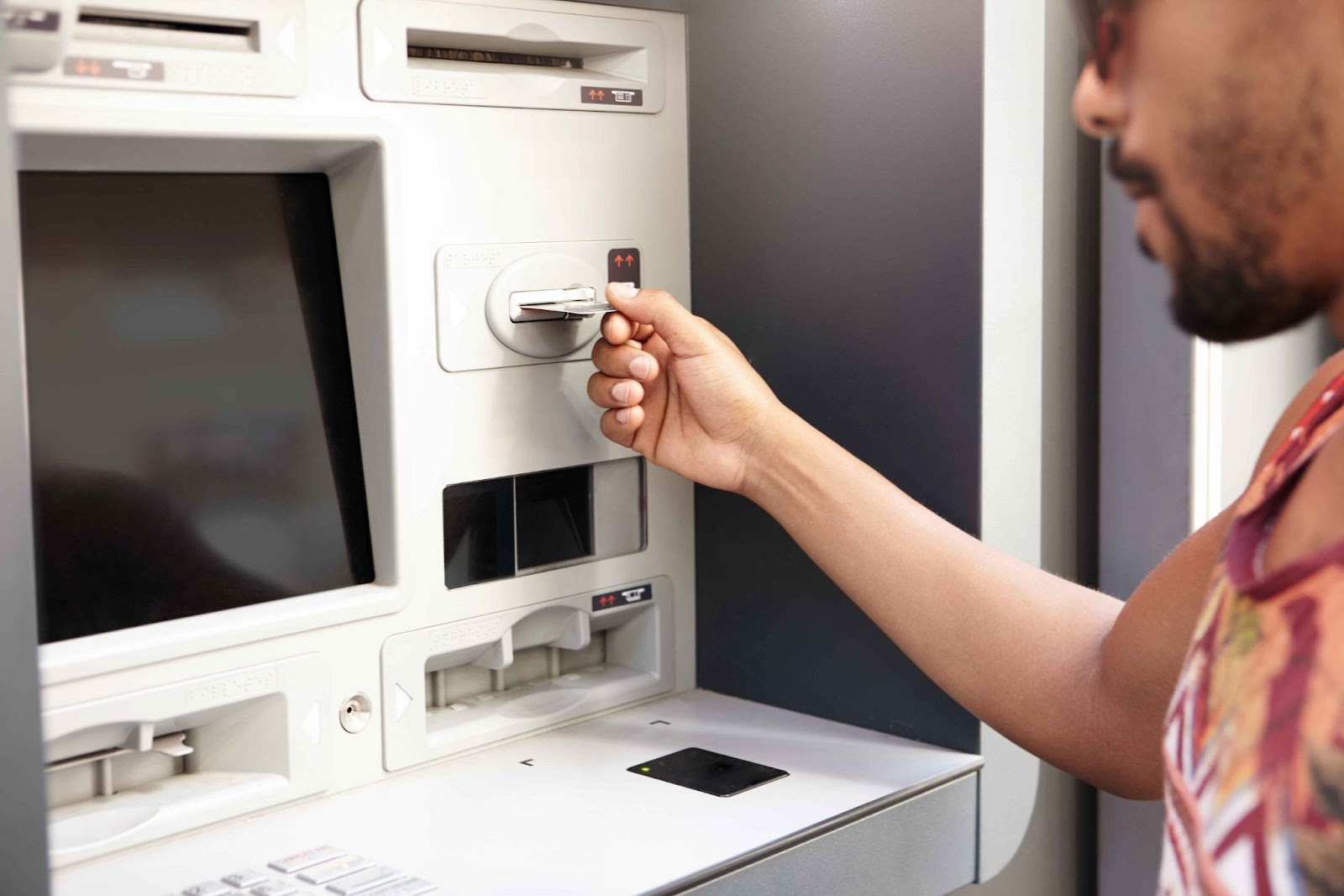 Close-up of a person inserting a card into an ATM, demonstrating how skimming devices can steal card data