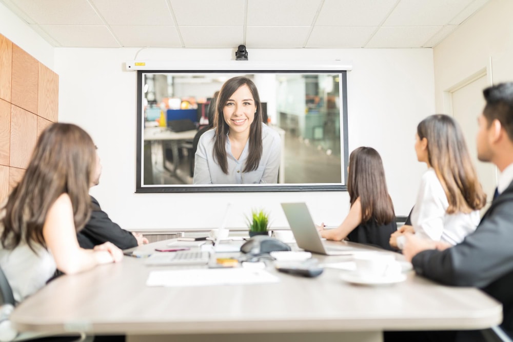 A professional team conducts a video meeting with a client, highlighting a common application of UCaaS video features.