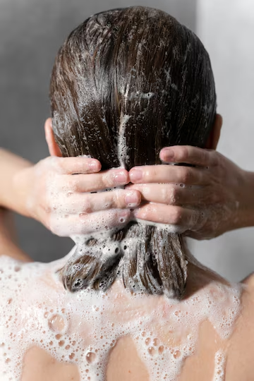 Young woman applying anti frizz shampoo