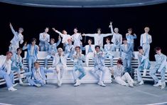 This  contain a group of  SM Entertainment sitting on top of white benches in front of a black background