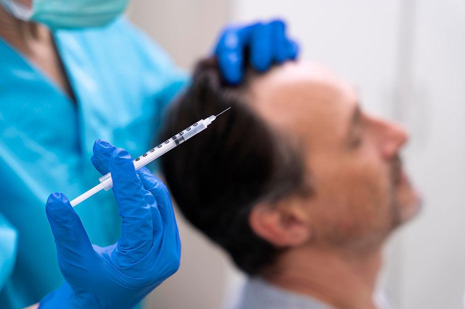 A surgeon is holding syringe in her hand to inject a patient
