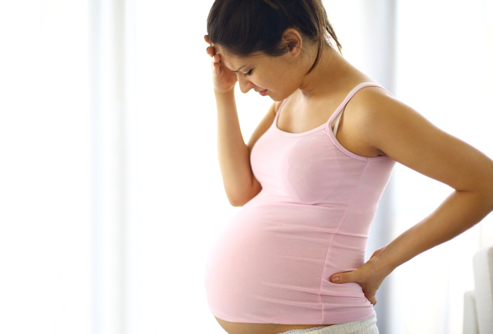 Pregnant woman wearing a pink camisole