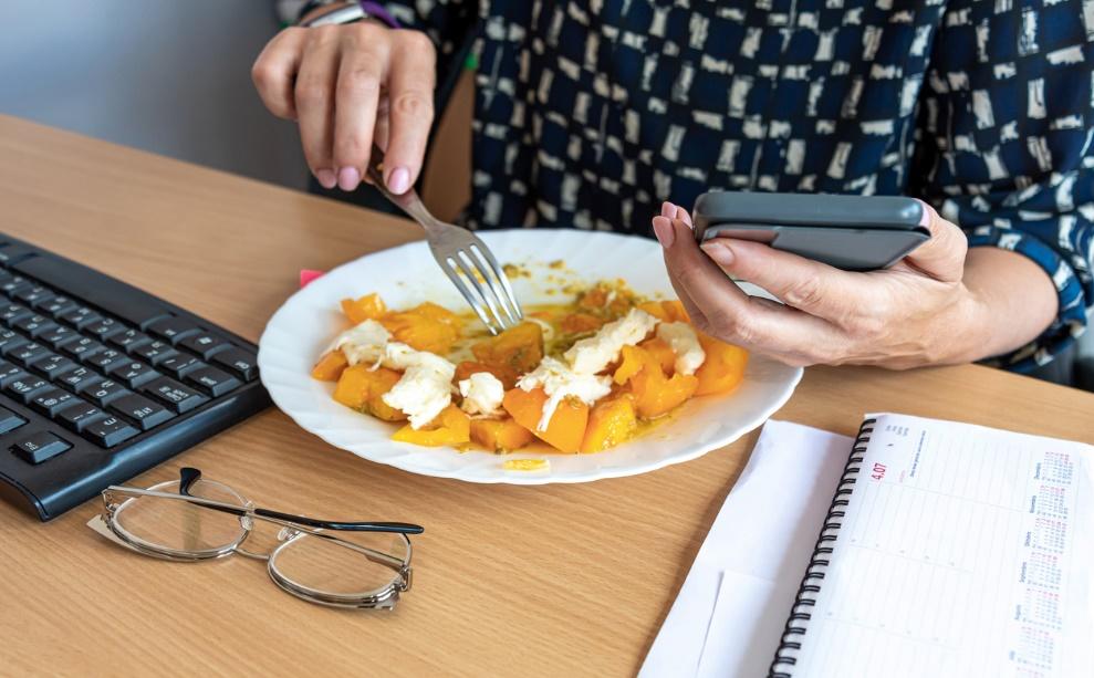 A person eating food with a phone

Description automatically generated