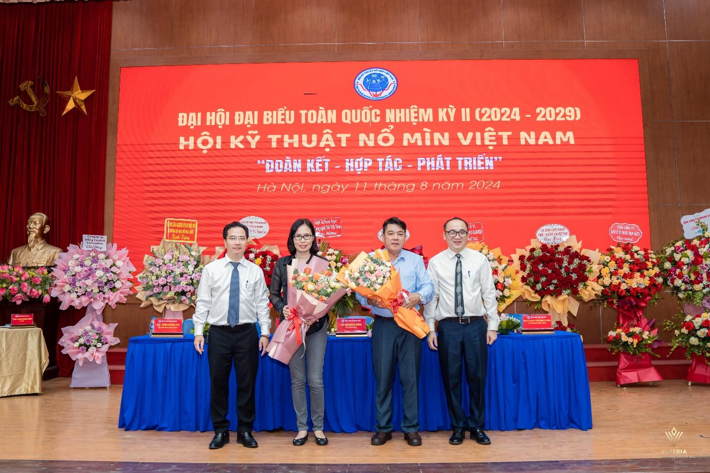 A group of people standing in front of a large banner

Description automatically generated