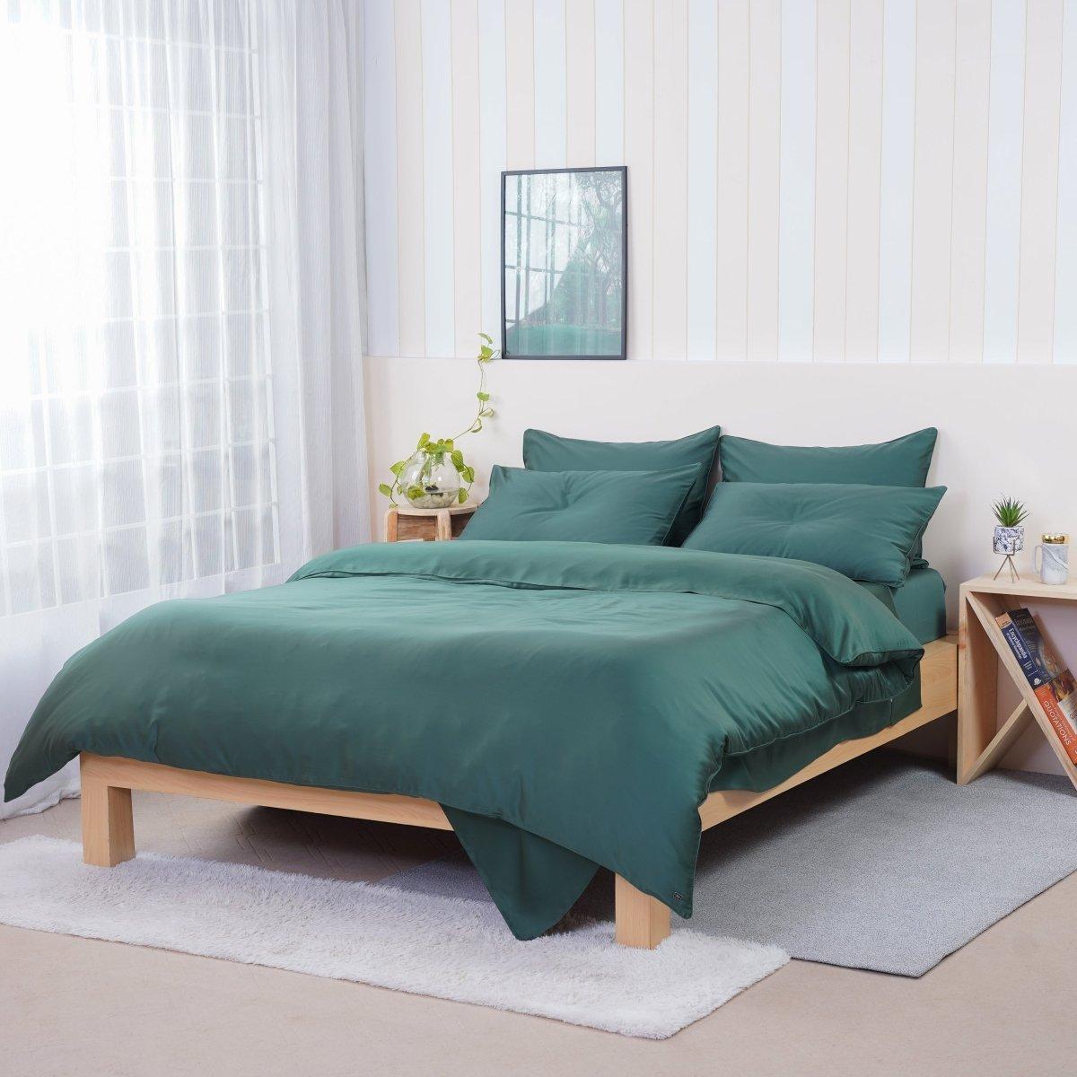 A bed with green comforter and pillows

Description automatically generated