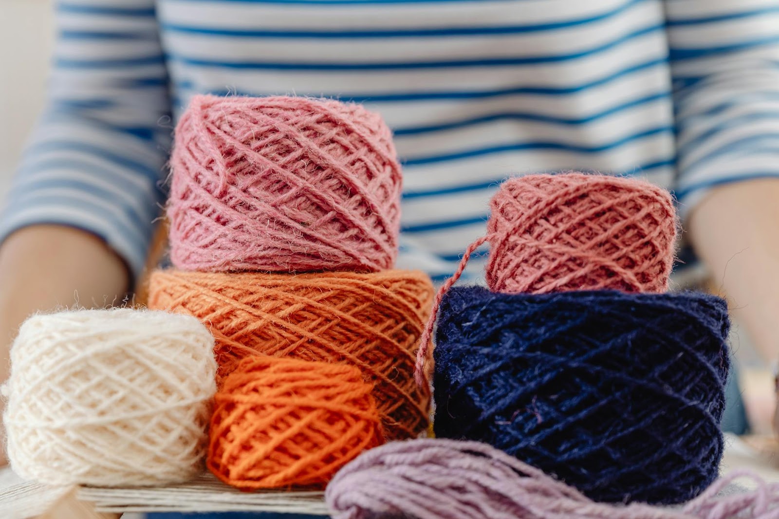 Person Holding Piles of Wool Thread Bobbins