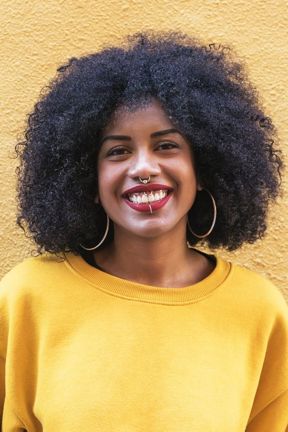 A black girl smiling and showing her spetum piercing