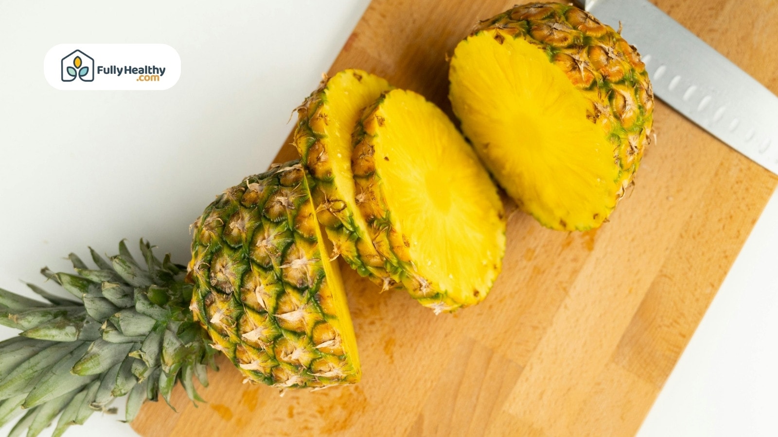 Fresh pineapple sliced on wooden cutting board with knife