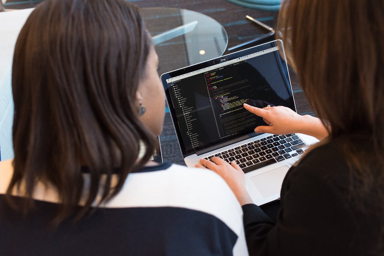 Two women looking at code on a laptop 