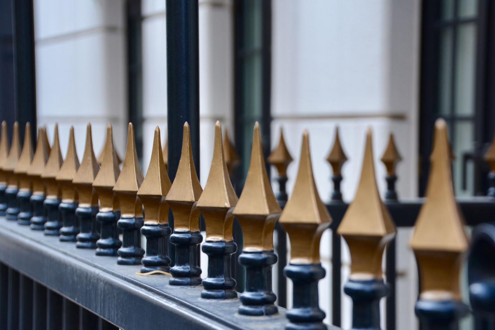 A close-up of a metal fence painted in black and bronze.