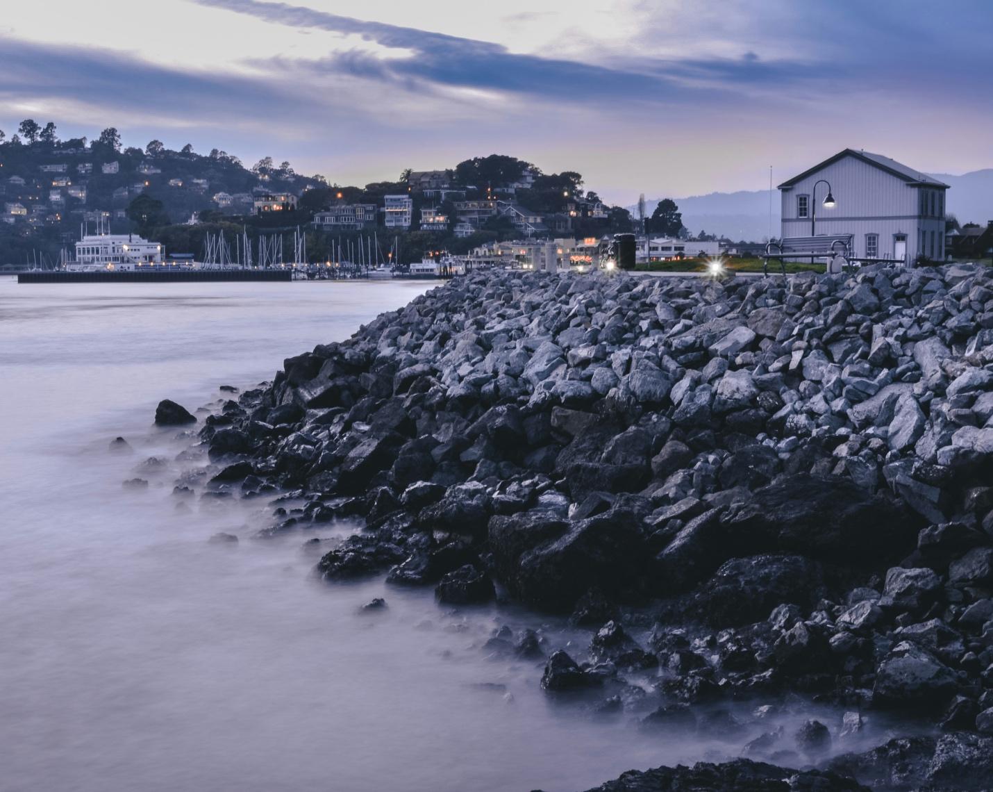 A rocky shore with a building in the background  AI-generated content may be incorrect.