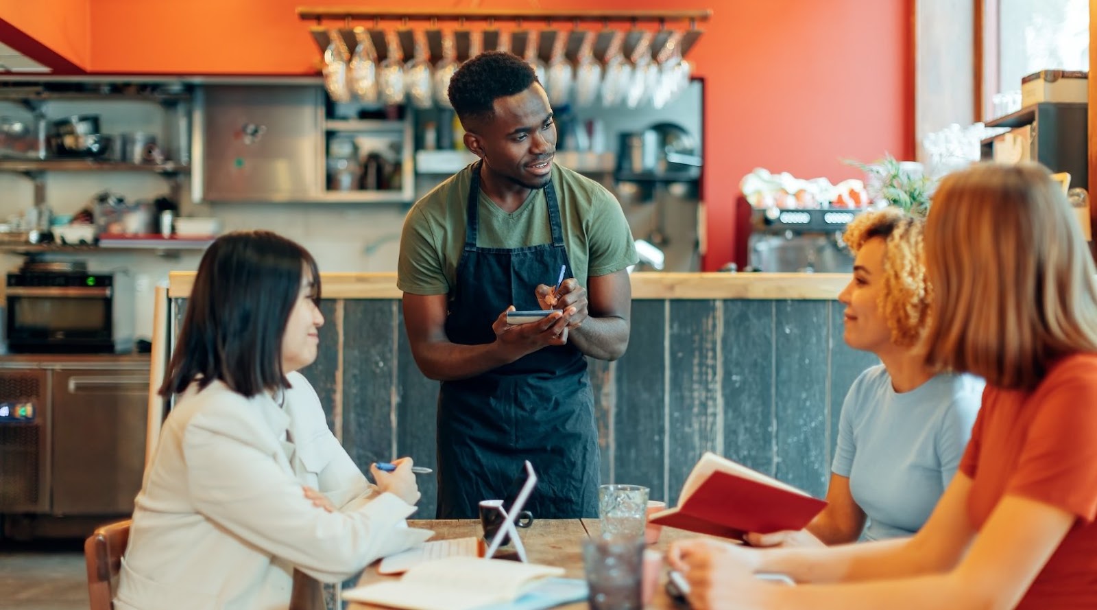 A friendly waiter taking an order at a highly recommended healthy restaurant near me, focusing on health-conscious options