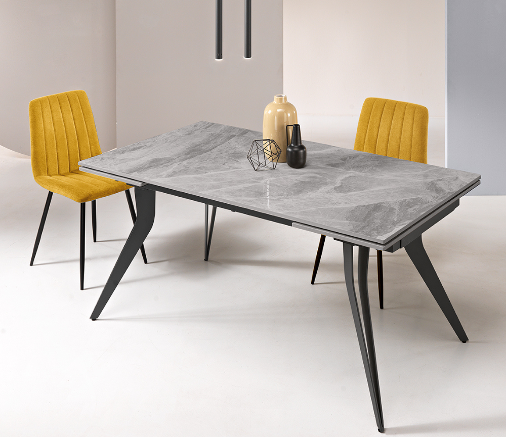 Table en céramique grise avec pieds noirs et chaises jaunes, illustrant les avantages et inconvénients à bien considérer avant de choisir une table en céramique pour un intérieur moderne.