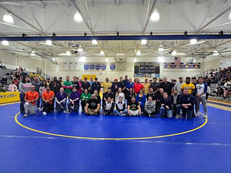 Group shot of staff members at a girls wrestling tournament at Lewis High School.