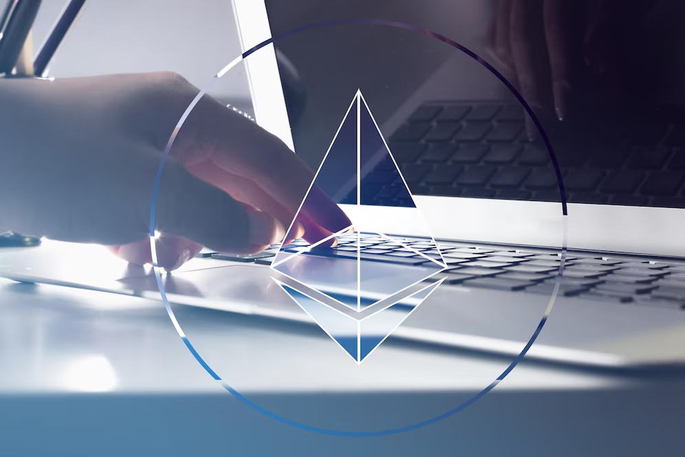 Ethereum logo in the foreground with a hand and a laptop 