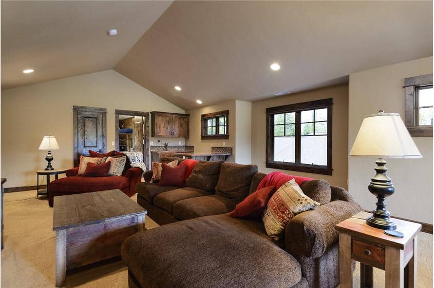 Bonus room with an L-shaped sectional, a red armchair, a rustic coffee table, and side tables topped with table lamps.