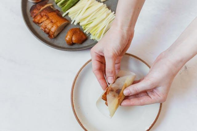 A person's hands holding a plate of food

Description automatically generated