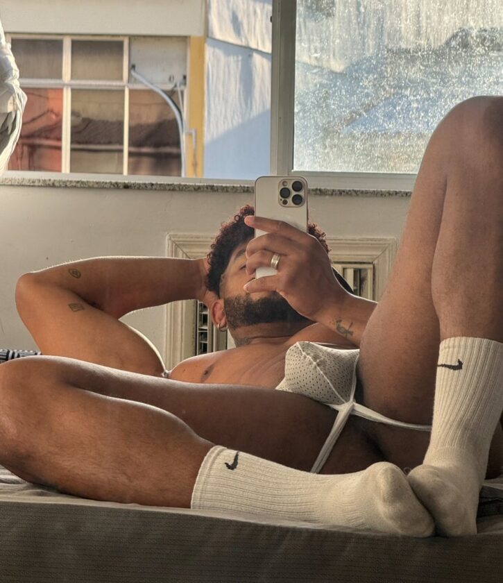 Lipe Scorpio posing on the bed taking gay onlyfans photos in white nike athletic socks and a mesh white jockstrap