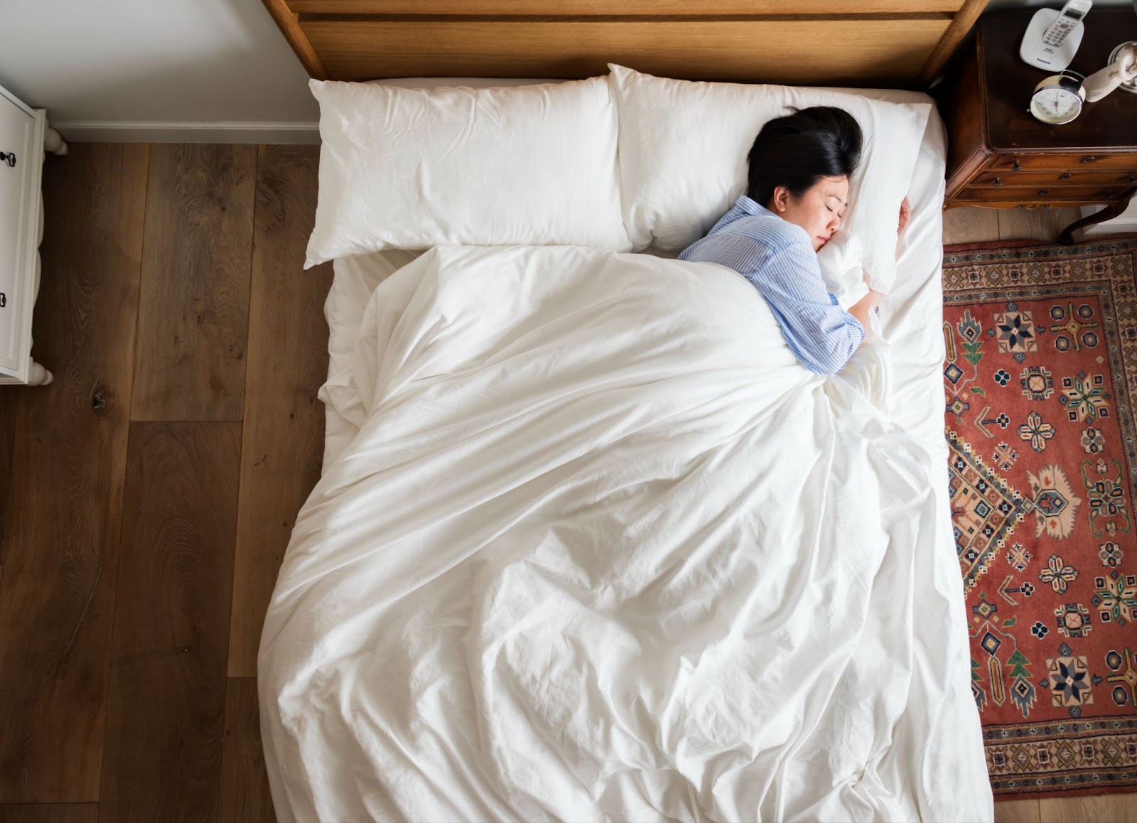 A woman sleeping peacefully alone in bed, highlighting how sleep positions can influence choosing between latex foam vs memory foam.