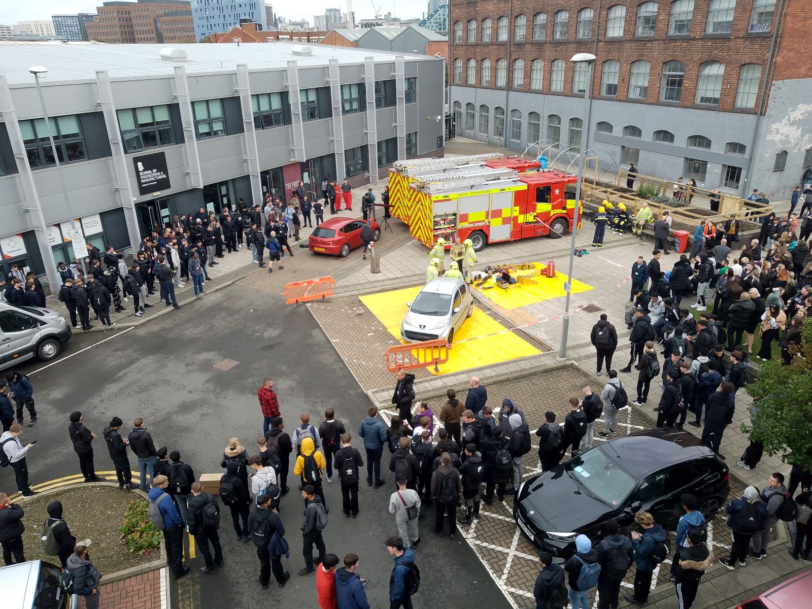 two fire engines in printworks car park with a silver car surrounded by a crowd of people