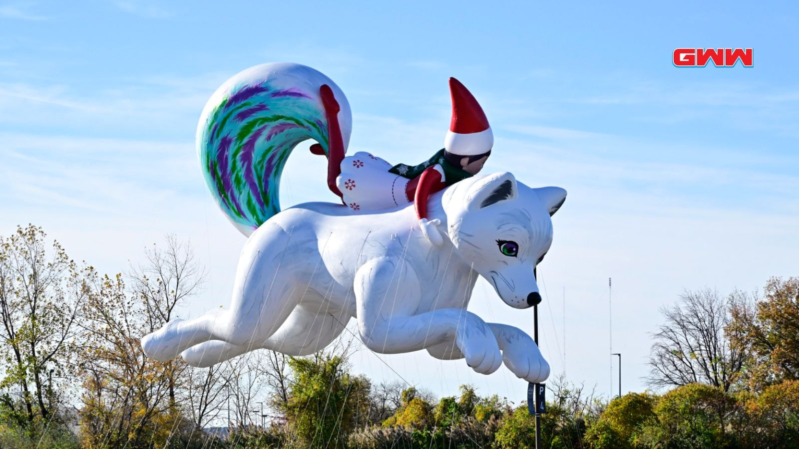 Elf riding a large white fox balloon in the parade.