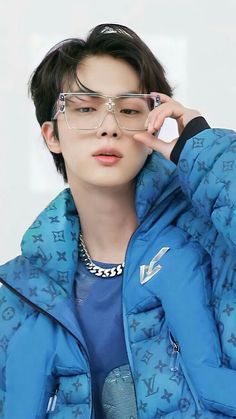 This contains an image of Kim Seokjin on blue cloth and his hand on his eye glass 