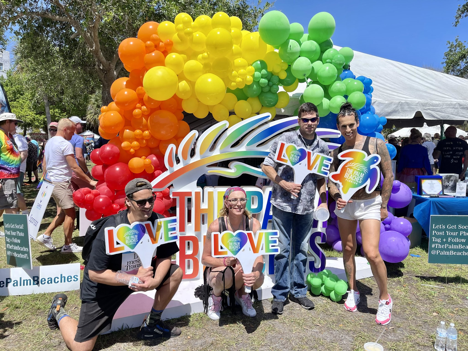 Eine Gruppe von Menschen, die das LGBTQ-Festival auf der Palm Beach Pride-Veranstaltung feiern, posiert vor einem bunten Luftballonbogen mit einem "LOVE The Palm Beaches"-Schild.