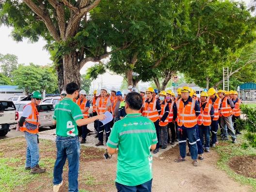 A group of people in orange vests and helmets standing in a line

Description automatically generated