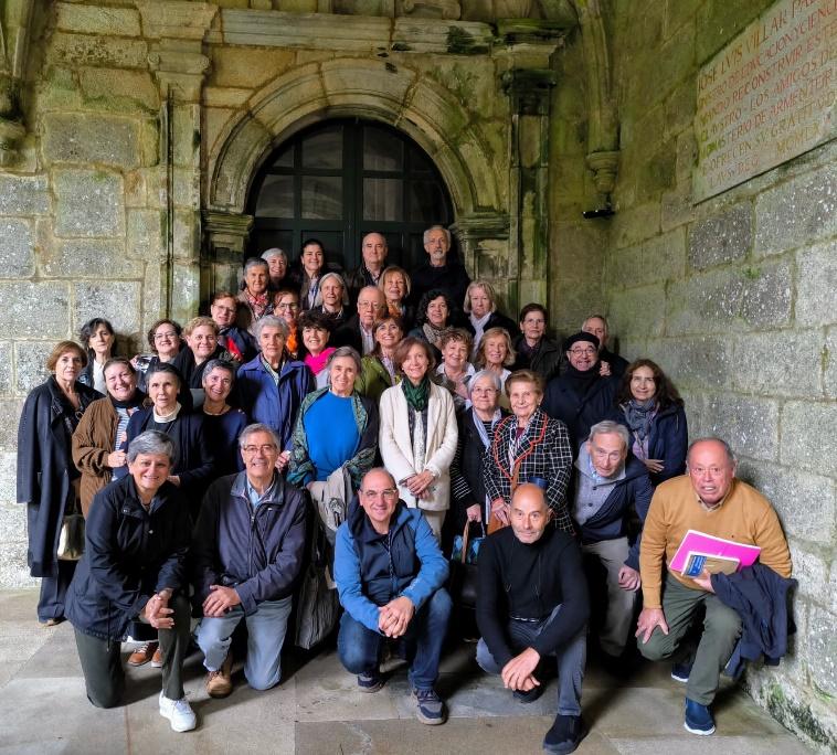 Un grupo de personas posando delante de una pared de piedra

Descripción generada automáticamente